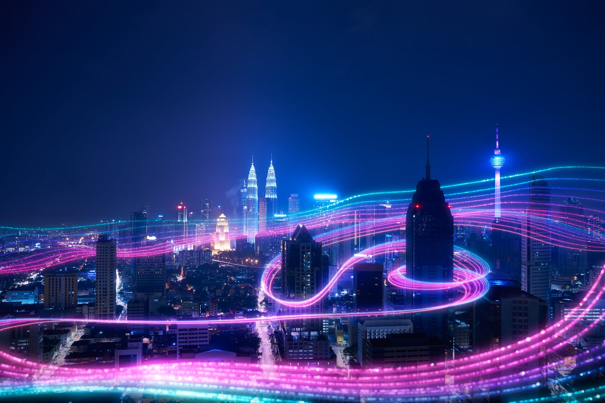 Streams of data whiz around tall buildings in a city at night